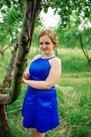 Young overweight girl at blue dress posed background spring garden. photo