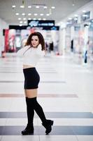 Young curly model girl posed on mini skirt at large shopping center. photo