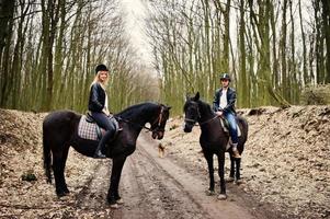 Young stylish couple riding on horses at autumn forest. photo