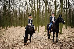 joven pareja con estilo montando a caballo en el bosque de otoño. foto