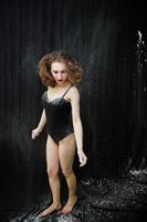 Girl dancer jumping and dancing in the white dust with flour on a black background. Studio shot of woman dancing with flour. photo