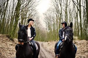 joven pareja con estilo montando a caballo en el bosque de otoño. foto