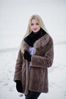 retrato de joven elegancia chica rubia en un abrigo de pieles río niebla de fondo en el hielo de invierno. foto