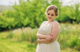 Young overweight girl at beige dress posed background spring garden. photo