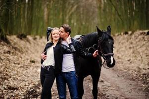 joven pareja elegante enamorada cerca de caballo en el bosque de otoño. foto