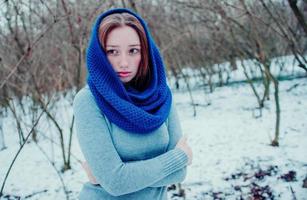 retrato de una joven pelirroja con pecas usando una bufanda de lana de punto azul en el día de invierno. foto