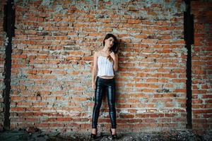 Portrait of young cute brunette girl background brick wall. photo