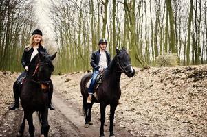 Young stylish couple riding on horses at autumn forest. photo