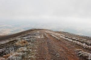 Mountainsides with frozen grass and fog on hill. photo