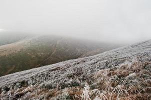 Mountainsides with frozen grass and fog on hill. photo