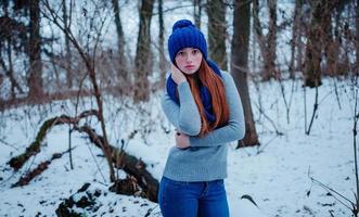 Portrait of young red hair girl with freckles wearing at blue knitted wool hat and scarf in winter day. photo