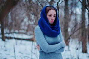 retrato de una joven pelirroja con pecas usando una bufanda de lana de punto azul en el día de invierno. foto