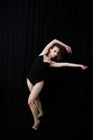 Girl dancer jumping and dancing on a black background. Studio shot of woman dancing. photo