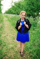 Young overweight girl at blue dress posed background spring garden. photo