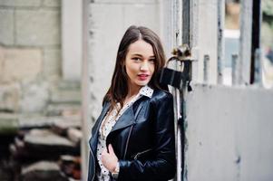 Portrait of stylish young girl wear on leather jacket and ripped jeans at streets of city. Street fashion model style. photo