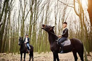 Young stylish couple riding on horses at autumn forest. photo