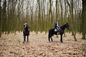 Young stylish couple riding on horses at autumn forest. photo