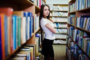 Brunette girl at library, wear on white blouse and black mini skirt. Sexy business woman or teacher concept. Black and white photo. photo