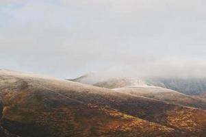 hermoso paisaje de la cima de la montaña con nieve, niebla y luz solar. foto