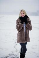 retrato de joven elegancia chica rubia en un abrigo de pieles río niebla de fondo en el hielo de invierno. foto