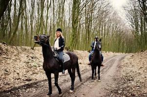 joven pareja con estilo montando a caballo en el bosque de otoño. foto