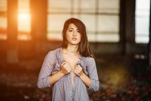 Cierra el retrato de una joven morena linda con un busto ligeramente posado en un lugar abandonado. foto