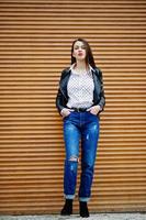 Full length portrait of stylish young girl wear on leather jacket and ripped jeans background shutter texture. Street fashion model style. photo