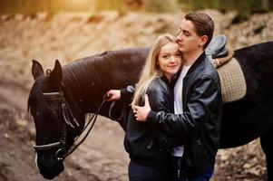 Young stylish couple in love near horse at autumn forest. photo