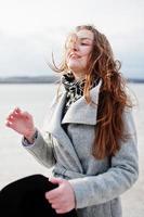 Happy funny model girl on gray coat with black hat on hand. photo