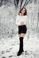 chica morena rizada fondo nieve cayendo, usar minifalda negra y medias de lana. modelo en invierno. retrato de moda en tiempo de nieve. foto en tonos de instagram.