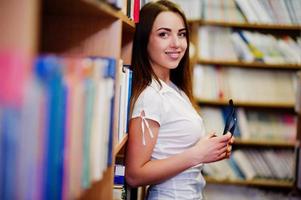 Brunette girl at library with glasses on hand, wear on white blouse and black mini skirt. Sexy business woman or teacher concept. Smile on braces.