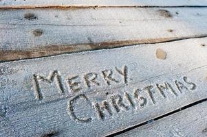 feliz navidad escrita sobre un fondo de madera con heladas foto