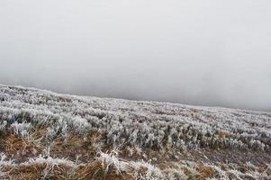 Mountainsides with frozen grass and fog on hill. photo