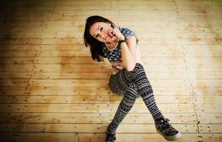 Street dancer girl wearing casual clothes on footless sitting background wooden parquet indoor. photo
