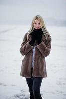 retrato de joven elegancia chica rubia en un abrigo de pieles río niebla de fondo en el hielo de invierno. foto