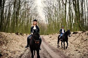 joven pareja con estilo montando a caballo en el bosque de otoño. foto