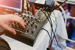 mano del hombre en la mesa de mezclas digital. panel de control del mezclador de sonido, primer plano de los faders de audio. foto