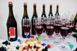 champán rojo sobre fondo de copas botellas en recepción. foto