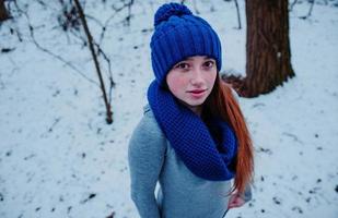 Portrait of young red hair girl with freckles wearing at blue knitted wool hat and scarf in winter day. photo