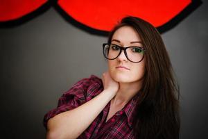 Portrait of brunette girl on glasses wearing casual clothes background gray wall with some graffity. photo