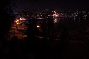 panorama de las luces de la ciudad nocturna y reflejos en el lago en ternopil, ucrania, europa. foto