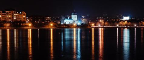 panorama de las luces de la ciudad nocturna y reflejos en el lago en ternopil, ucrania, europa. foto