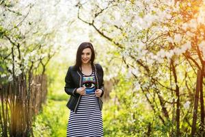 chica morena con chaqueta de cuero posada en el jardín de primavera. foto