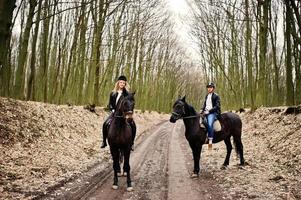 joven pareja con estilo montando a caballo en el bosque de otoño. foto