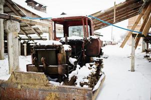 viejo tractor soviético oxidado cubierto de nieve. foto