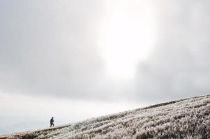 el hombre se levanta en la colina congelada de la montaña. foto