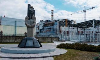 Monument of dying people in the tragedy of Chernobyl, background nuclear power plant photo