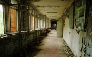 Abadoned school corridor with open windows at Chernobyl city zone of radioactivity ghost town. photo