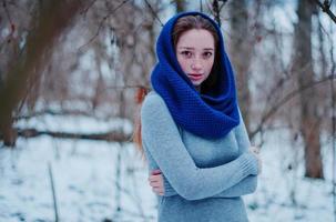 retrato de una joven pelirroja con pecas usando una bufanda de lana de punto azul en el día de invierno. foto