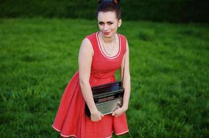 Portrait of young pinup girl wearing at retro vintage old-fashioned dress in peas with retro radio in hands photo